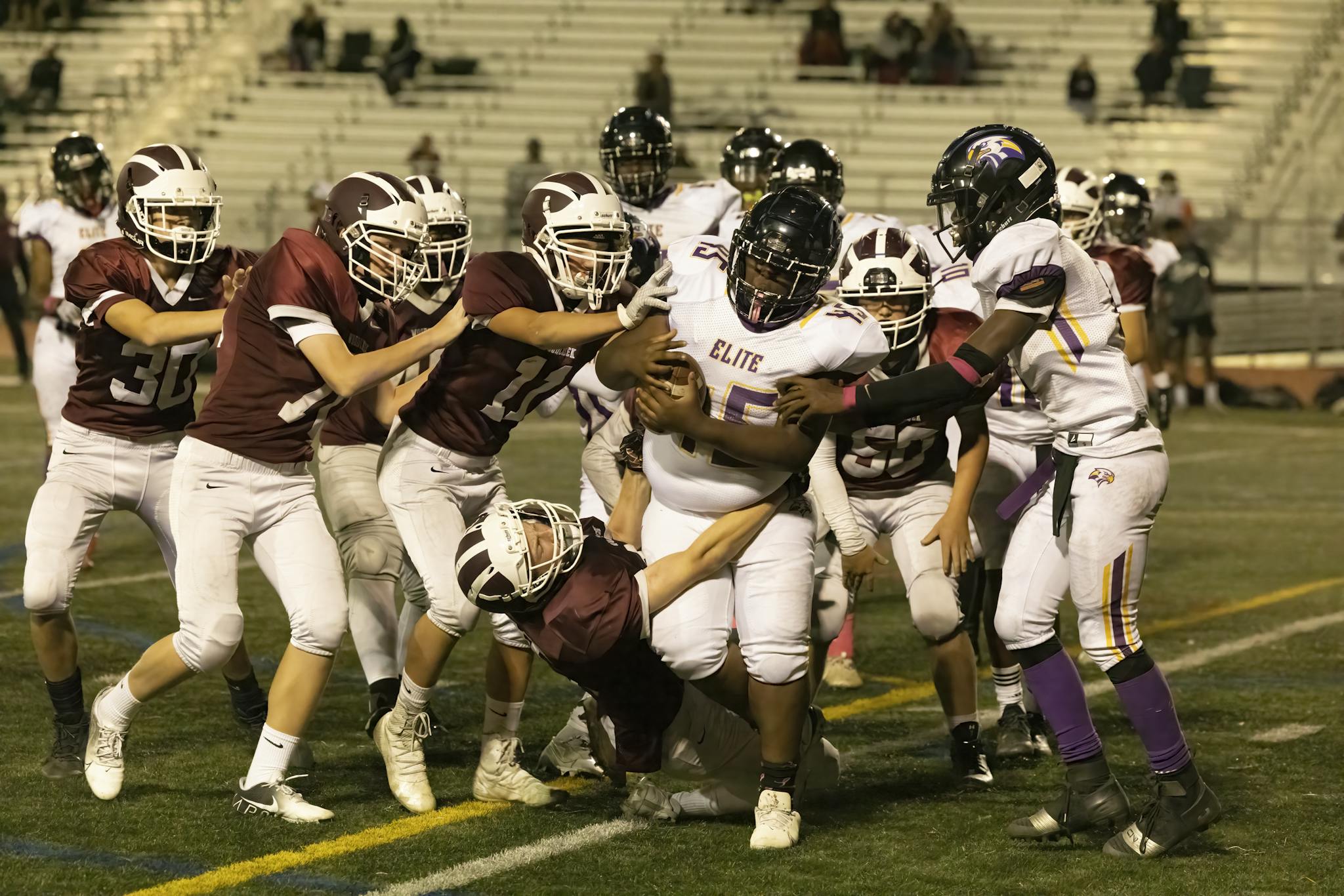 Intense high school football play with players in motion on the field.